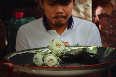 Close-up of man looking at flowers and hair in plate