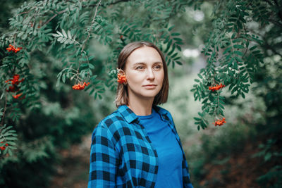 Portrait of young woman standing against plants