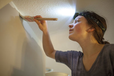 Low angle view of woman painting wall at home