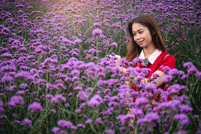 Beautiful young woman with purple flowers on field