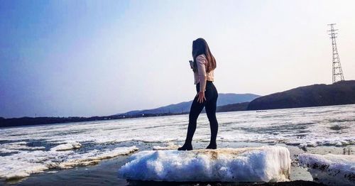 Woman standing on shore against clear sky