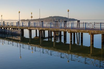 Pier on lake against clear sky during sunset