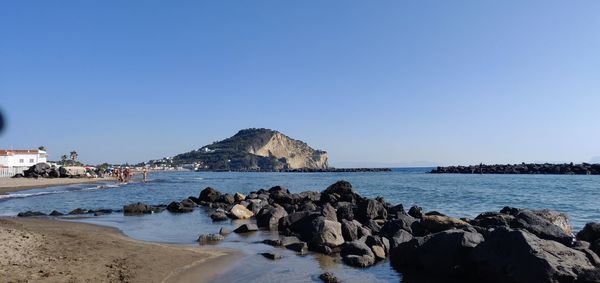 Rocks on beach against clear blue sky