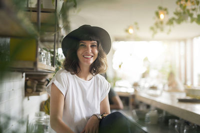 Portrait of woman with black hat behind the bar in a cafe