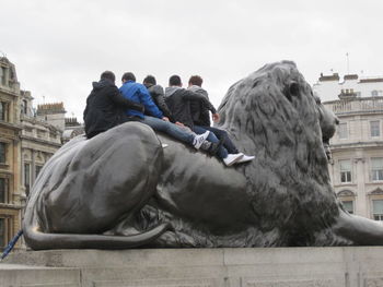 People sitting against sky in city