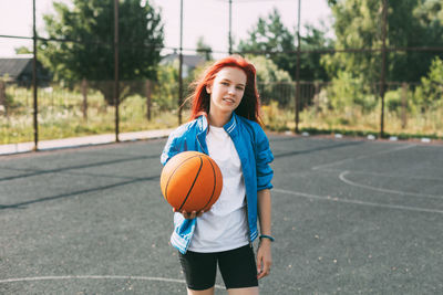 Portrait of a smiling teenage girl with a basketball on the sports field. sports, health, lifestyle