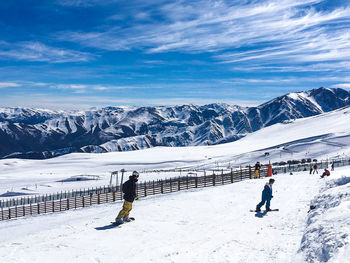 People on snowcapped mountain against sky