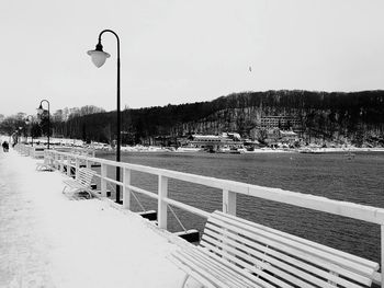 Road by river against clear sky during winter