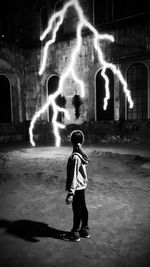 Full length of boy standing on illuminated city at night