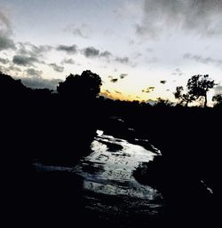 Silhouette trees on landscape against sky during sunset