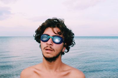 Portrait of shirtless man in sea against sky