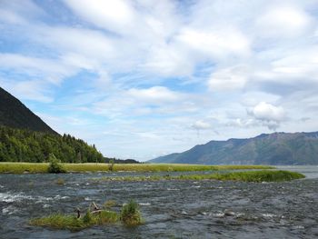 Scenic view of river by mountains against sky