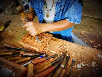 Midsection of man carving wood at carpentry