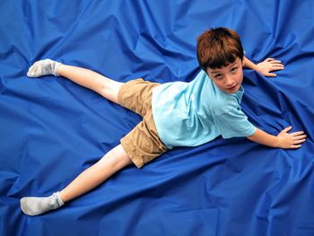 Portrait of boy lying on blue sheet