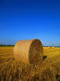 Hay bales on field against clear sky