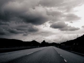 Empty road with empty road against cloudy sky