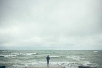 Rear view of man looking at sea against sky
