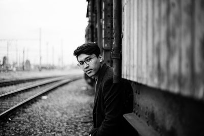 Portrait of young man standing against rusty train