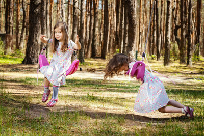 Sisters swinging against trees