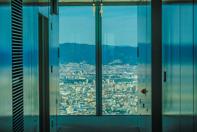 Buildings against sky seen through glass window