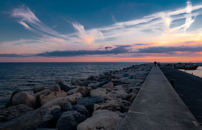 Scenic view of rocks and sea against sky during sunset