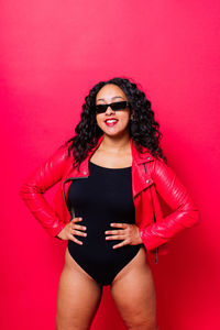 Portrait of young woman standing against yellow background