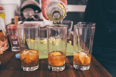 Cropped image of hand pouring drink in glass on table