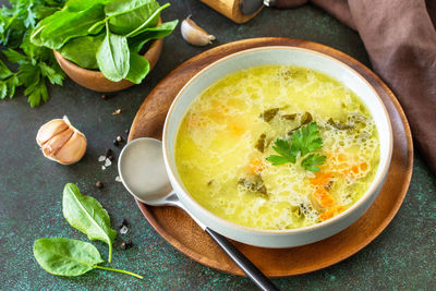 Spring menu. healthy spinach soup with cream on a dark stone countertop.