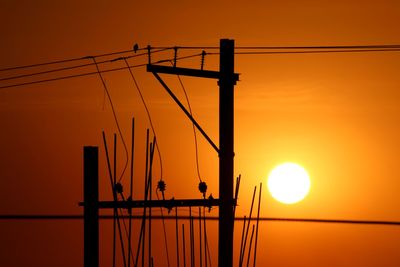 Silhouette cranes at construction site during sunset