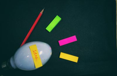 High angle view of light bulb by adhesive notes and pencil on table