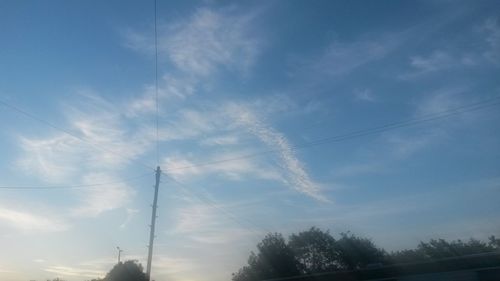 Low angle view of power lines against cloudy sky