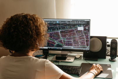 Rear view of businesswoman working on computer in office