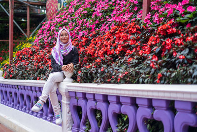 Portrait of woman sitting by flowering plants