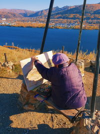 Rear view of woman painting river