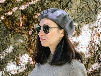 Millennial beautiful woman casual sweater and french beret stands by old tree confident young adult