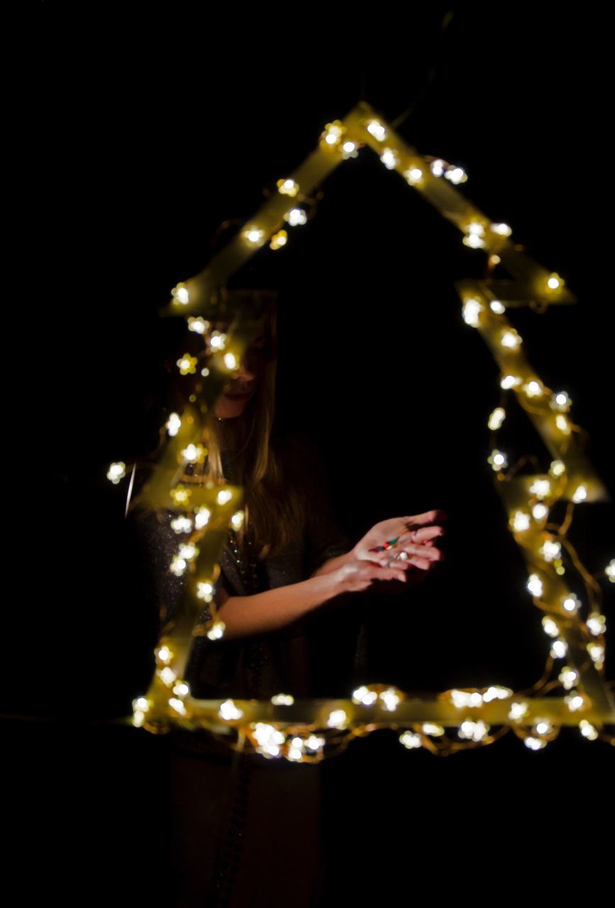 LOW ANGLE VIEW OF ILLUMINATED LIGHTING EQUIPMENT HANGING ON BLACK BACKGROUND