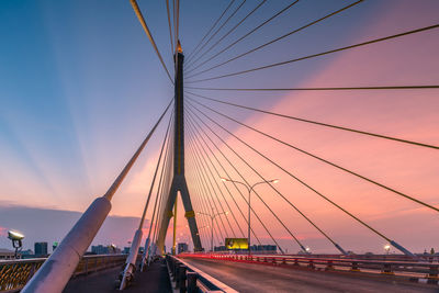 Light trails on illuminated rama viii bridge against cloudy sky at dusk in city