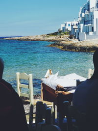 People sitting by sea against sky