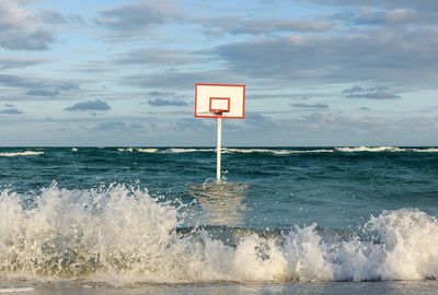 Basketball hoop in sea against sky
