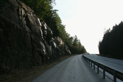 Road amidst trees against clear sky