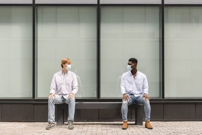 Multiracial friends maintaining social distance on bench