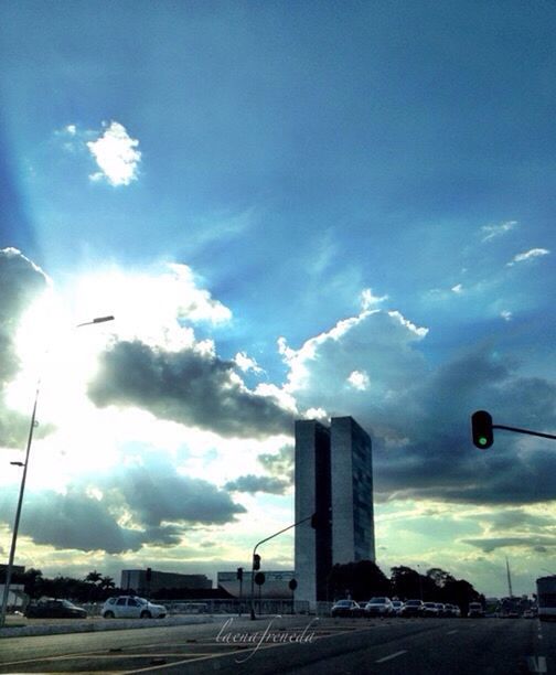 sky, building exterior, transportation, cloud - sky, built structure, architecture, car, street light, road, mode of transport, land vehicle, street, cloud, city, low angle view, cloudy, outdoors, blue, no people, sunlight