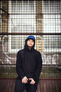 Portrait of confident man standing against fence