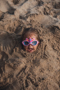 Portrait of young woman wearing sunglasses on sand at beach