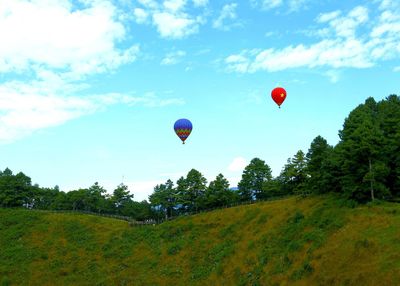 Hot air balloons flying over landscape against sky