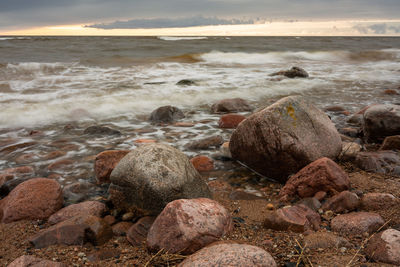 Rocks on beach against sky during sunset