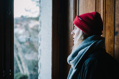 Young woman looking through window in winter