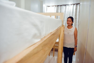 Front view of young woman standing by double deck bed