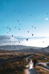 Rear view of people watching hot air balloons flying in sky