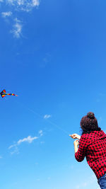 Low angle view of people against clear blue sky